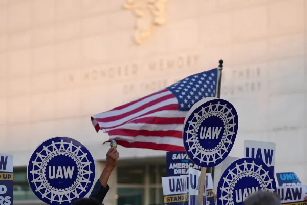 UAW Members Marching with US Flag in Background